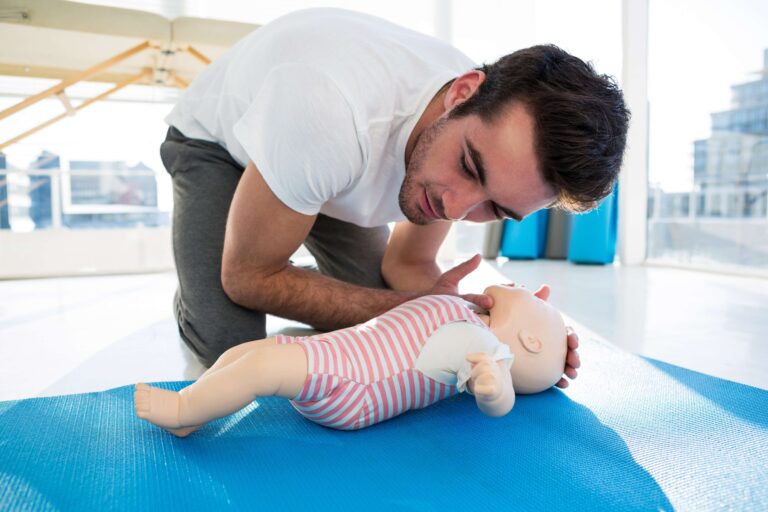 A man is teaching how to use an infant cpr manikin.