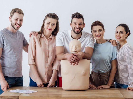 A group of people standing around an instructor 's dummy.